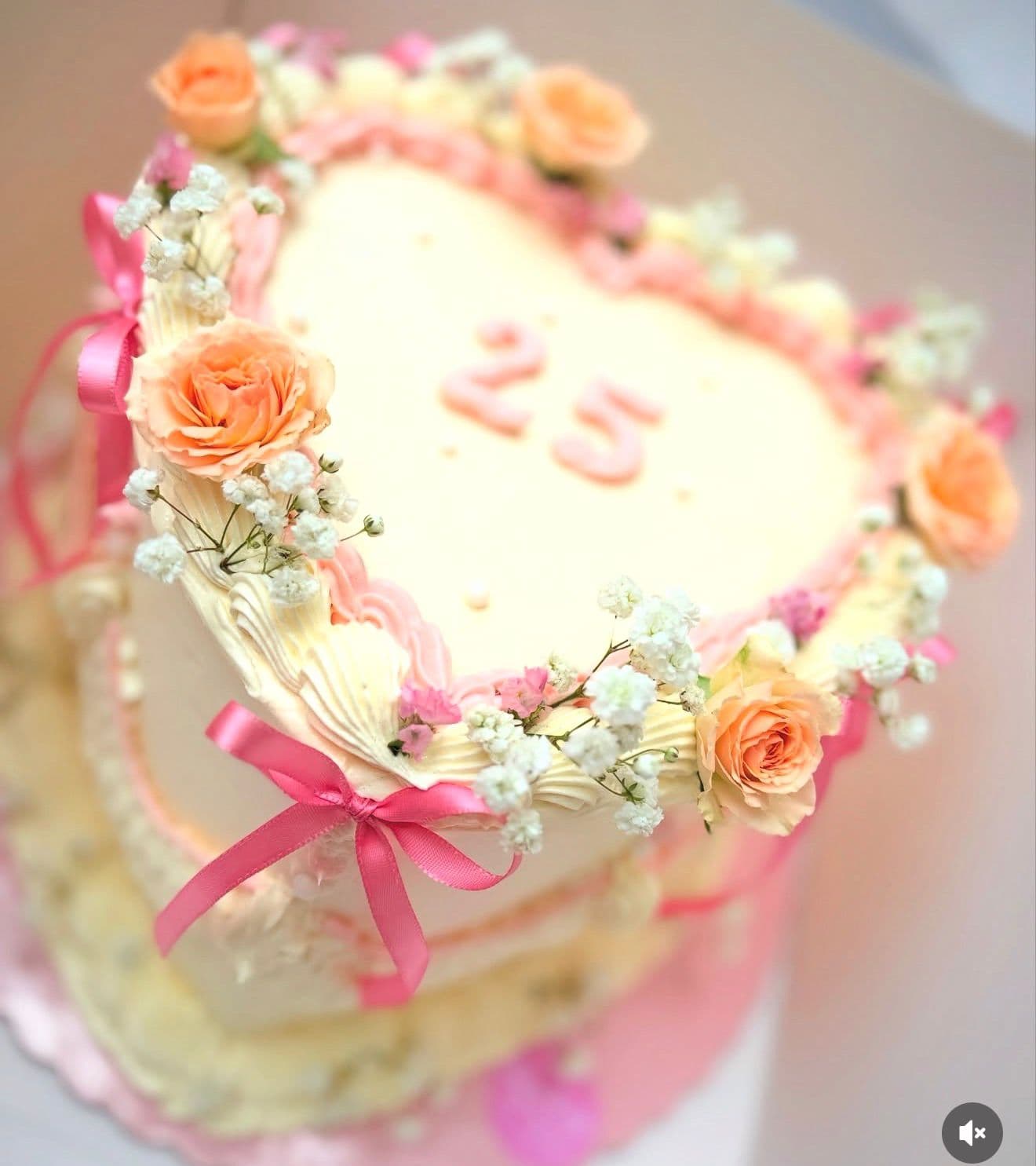 Tarta de corazón crema con flores de colores y lazo rosa