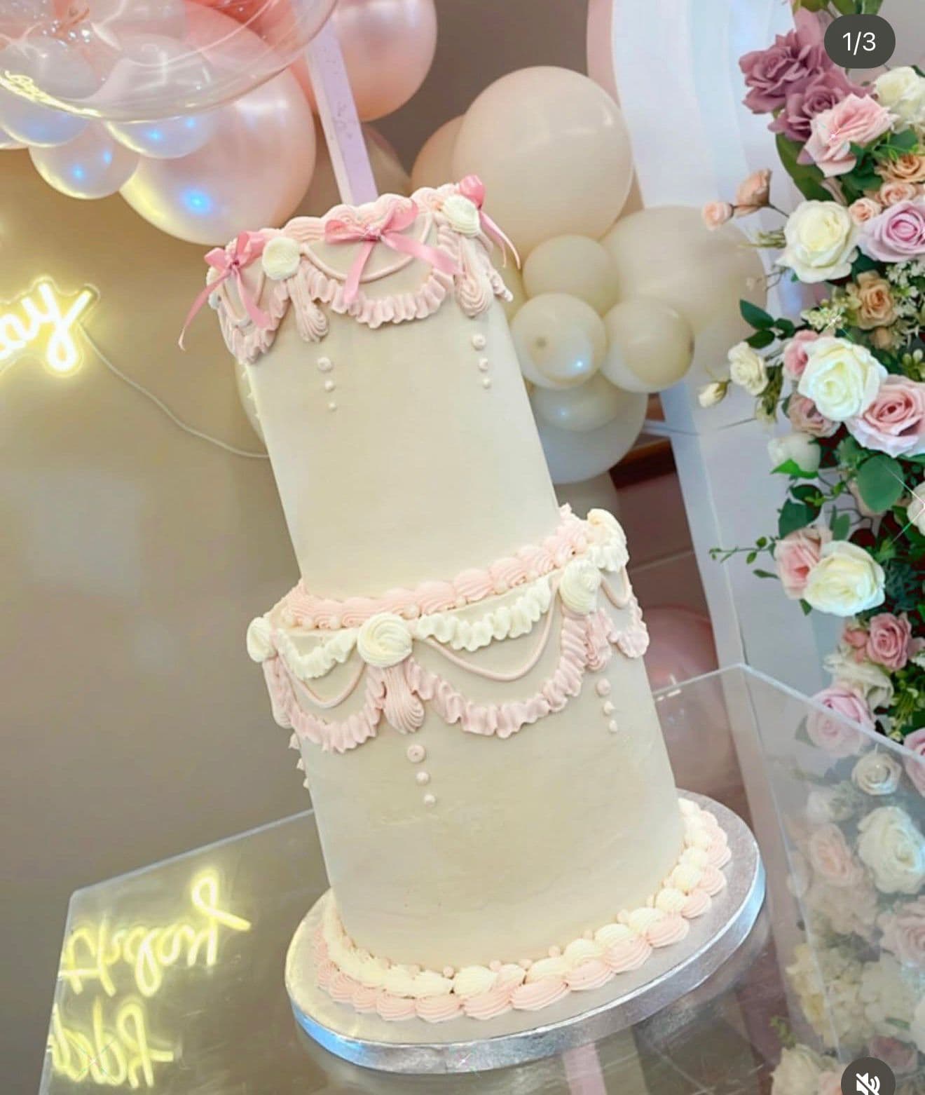 Tarta blanca de dos pisos con detalles rosas y flores delicadas