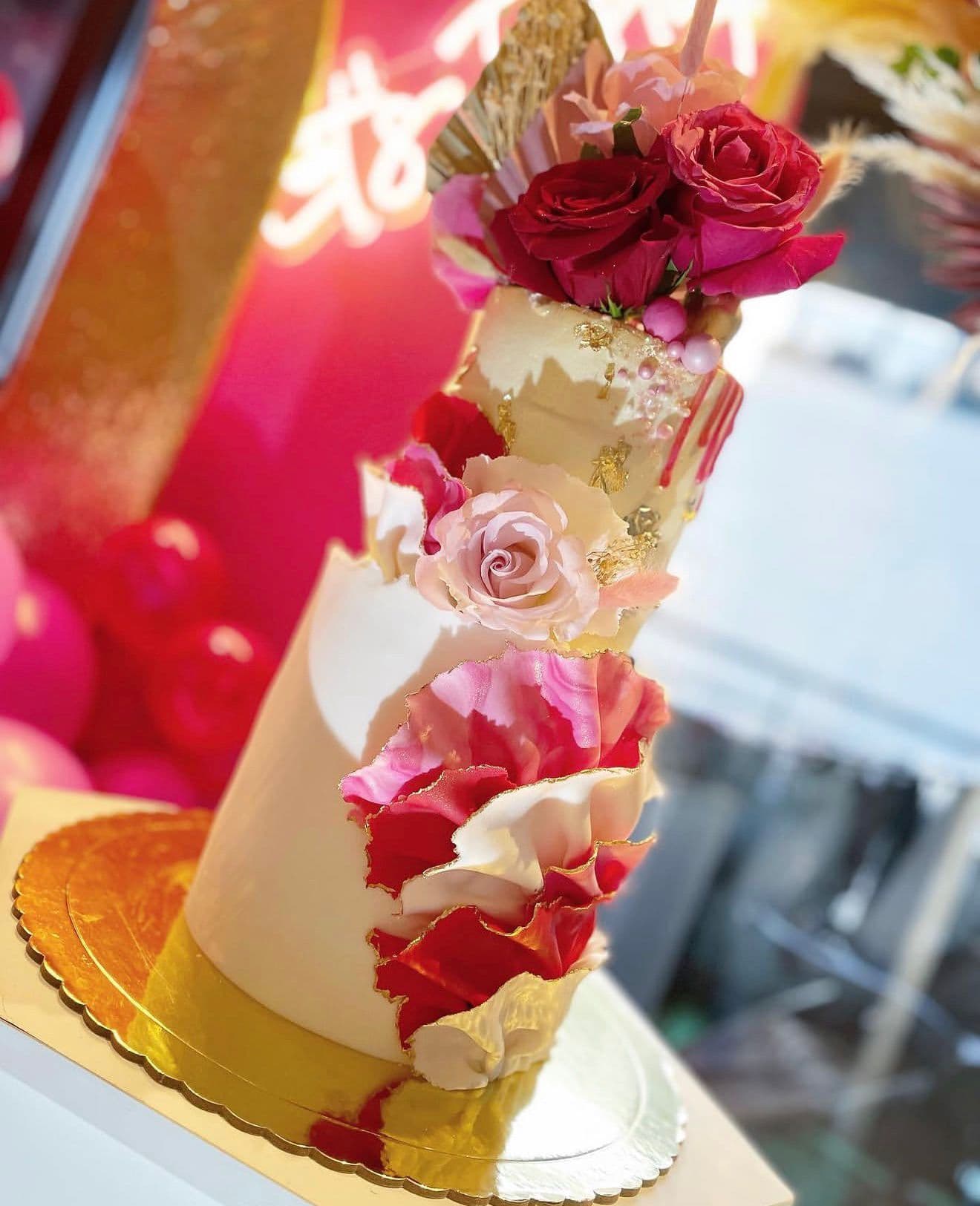 Tarta floral blanca con detalles rosas y flores rojas