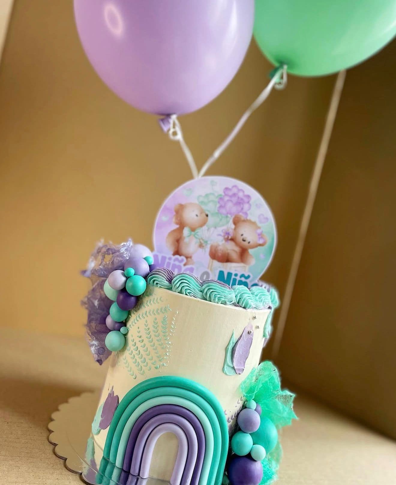 Tarta pastel con arcoíris, globos y decoración infantil